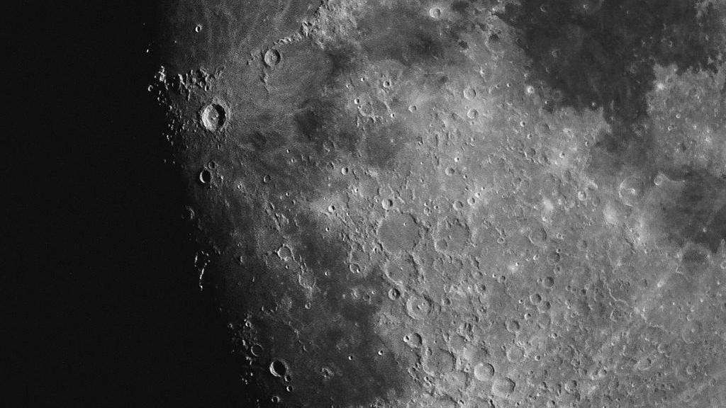 Close up shot of a grey lunar surface, with several craters.
