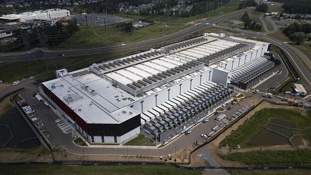 An aerial view of a large white data centre that takes up a whole block