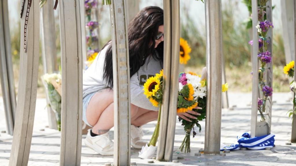 A woman laying flowers. 