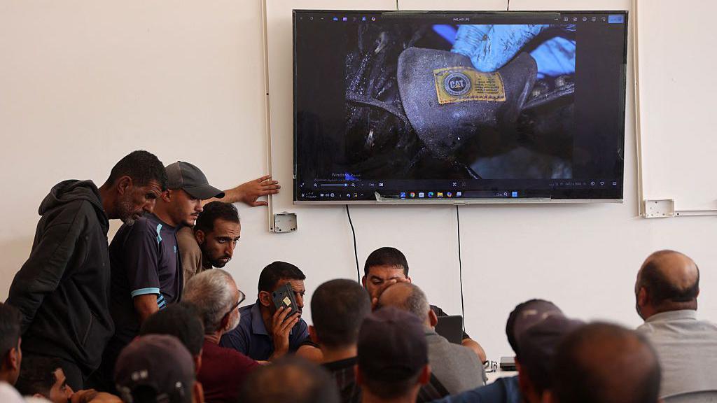 Officials show pictures of the bodies and personal items of Palestinians returned by Israel to relatives of missing people, at Nasser hospital, in Khan Younis, southern Gaza (18 October 2025)