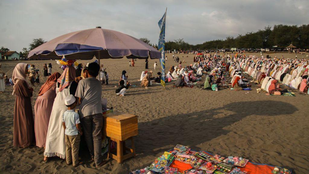 Muslims pray on a sand dune on a beach in Indonesia