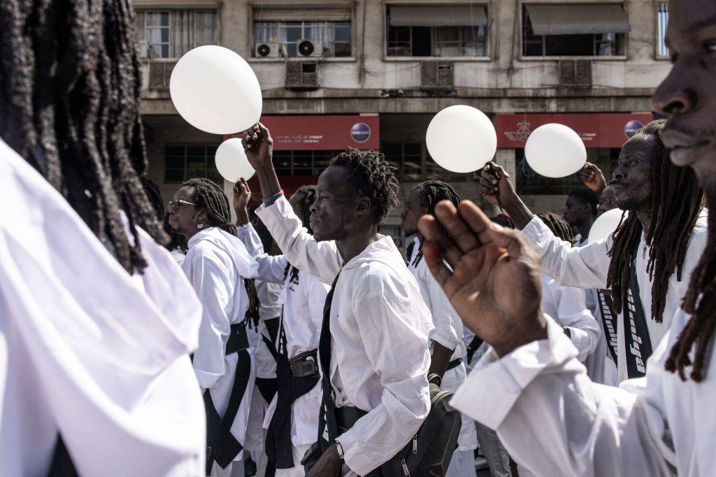 Followers of Amadou Bamba sing and march while wearing white robes and waving white balloons.