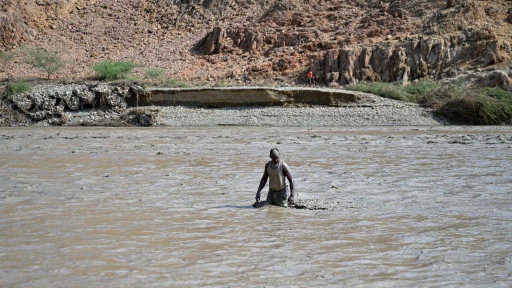 An image of a person wading through the muddy waters of the dam collapse