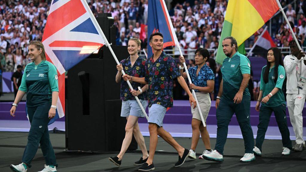 Alex Yee and Bryony Page carry the Great Britain flag in the Paris Olympics closing ceremony