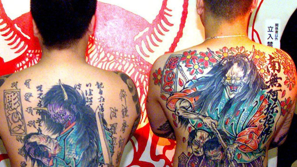 Two men with tattoos covering their backs