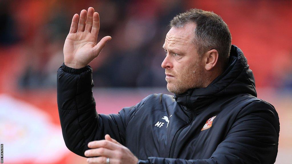 Michael Flynn waves to fans during their game with Crawley