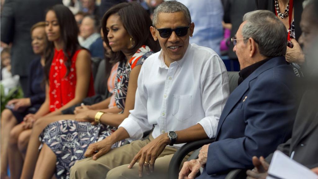 President Barack Obama, with members of his family, talks with Cuban President Raul Castro as they attend an exhibition baseball game between the Tampa Bay Rays and the Cuban National team at the Estadio Latinoamericano, Tuesday, 22 March 2016