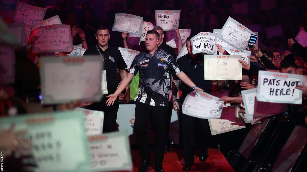 Darts player Chris Dobey walking past fans