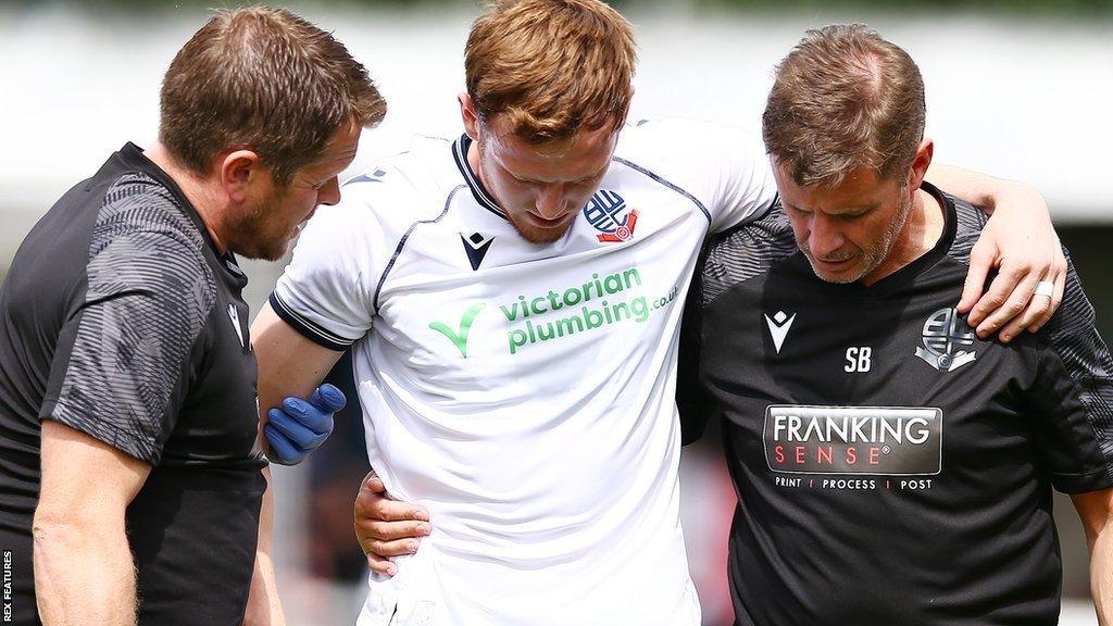 George Johnston (centre) is helped from the pitch after suffering a knee injury at Bamber Bridge