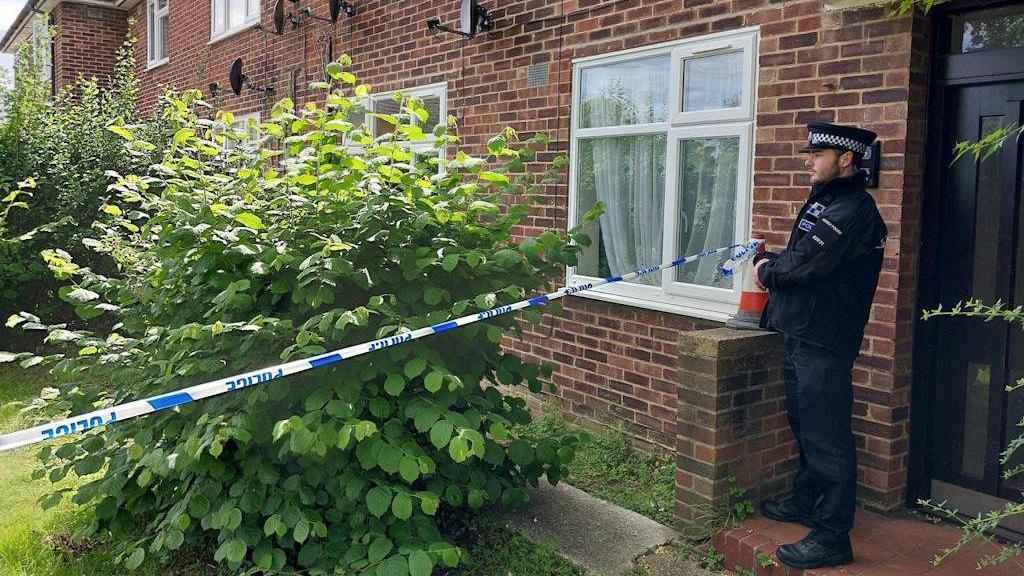 An Essex police officer standing behind an Essex Police cordon at a property in Loughton