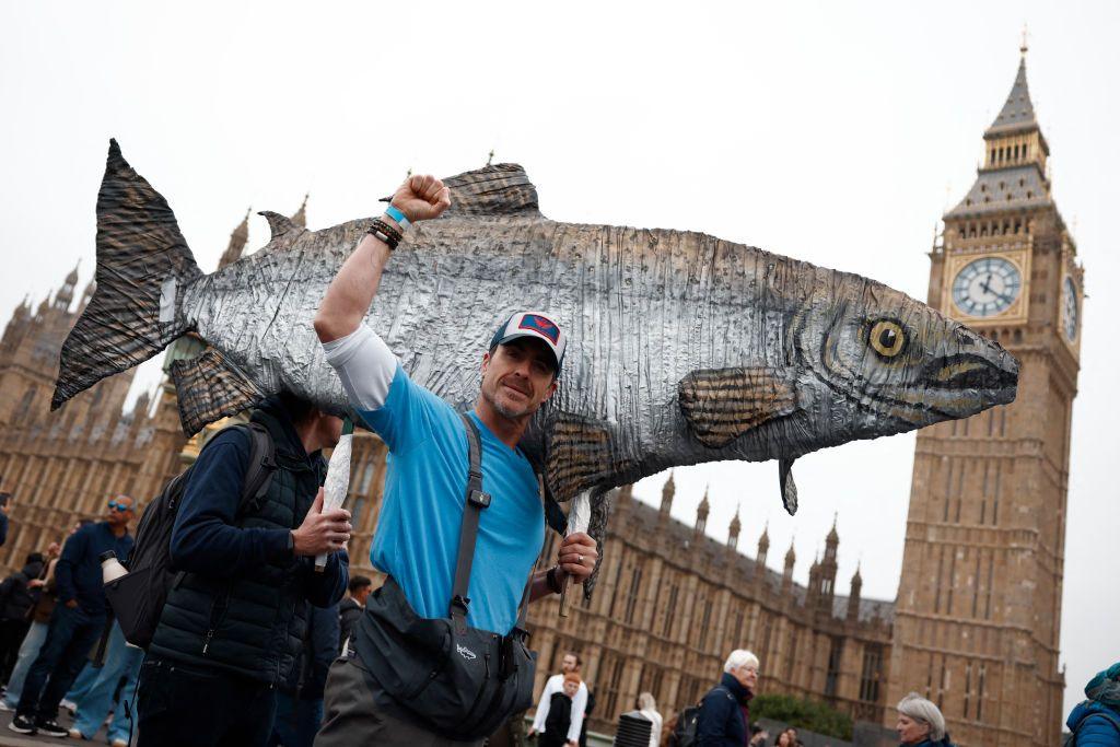 A man carries a model of a large fish on his shoulders as he passes Westminster
