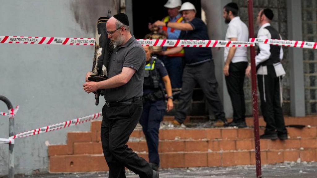 A member of the Jewish community recovers an item from the Adass Israel Synagogue on December 06, 2024 in Melbourne, Australia. An arson attack on the Adass Israel Synagogue in Melbourne forced congregants to flee as flames engulfed the building early on Friday morning.