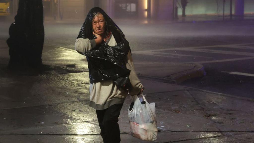 A woman walks through downtown as Hurricane Milton makes landfall on October 09, 2024, in Tampa