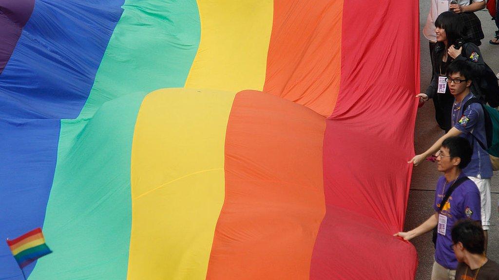 Giant rainbow flag being carried along street in Hong Kong