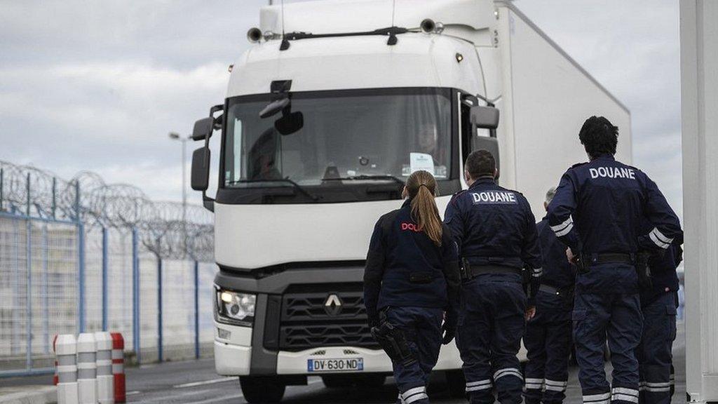 French Customs officers look on trucks arriving for embarkation at the port of Cherbourg, Normandy region, France