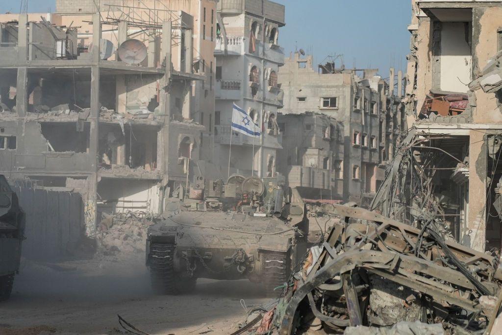 Israeli troops and an armoured personnel carrier patrol through the streets of a rubble-strewn Rafah in September 2024