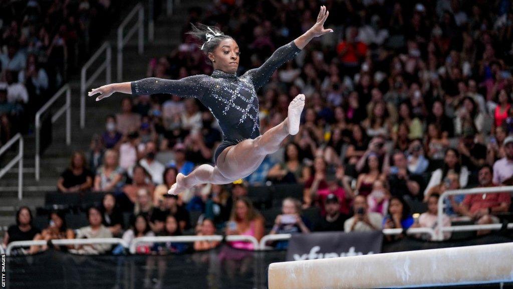 Simone Biles performs a split leap on the beam