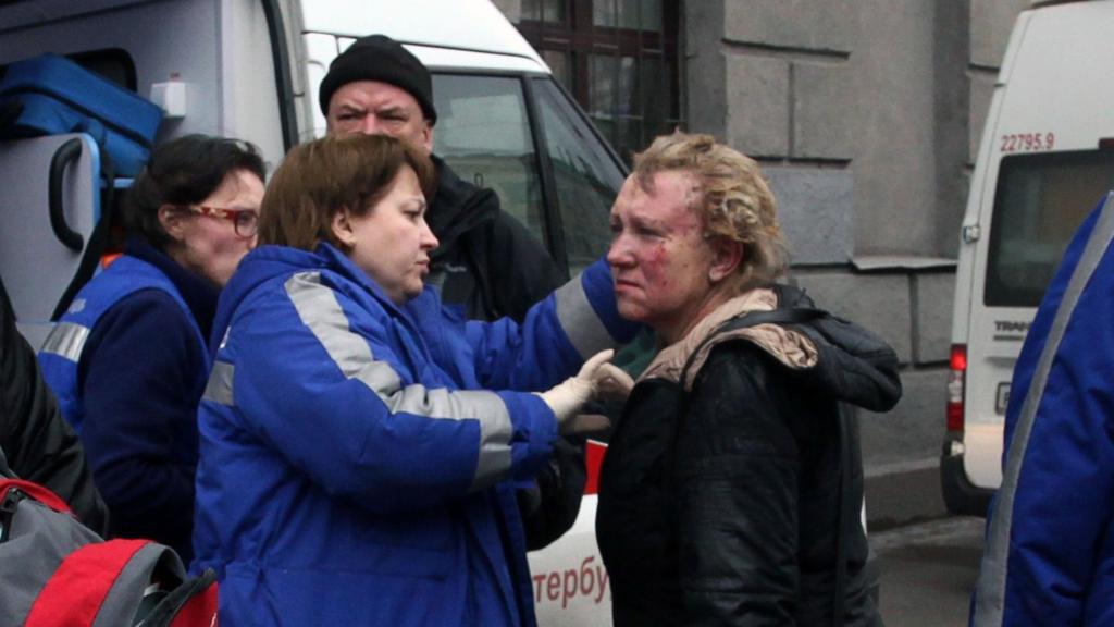 Medics help an injured woman outside Technological Institute metro station in Saint Petersburg