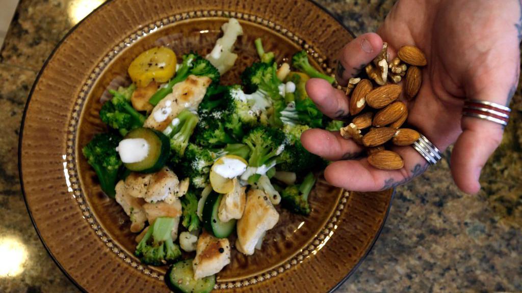A plate with a fasting meal which includes chicken, vegetables and nuts.