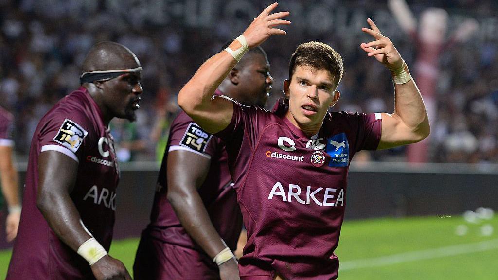 Matthieu Jalibert raises his arms as he wears Bordeaux's burgundy-coloured kit