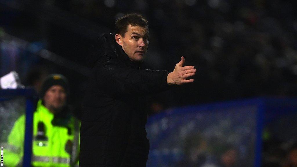 Matt Taylor holds his arm out while giving instructions from the dugout during Bristol Rovers' match with Exeter