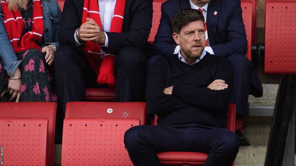 Darrell Clarke sits with his arms folded as he watches Cheltenham's defeat by Lincoln