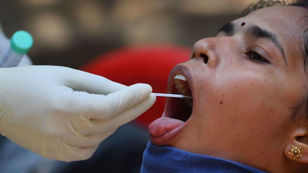 A doctor takes a swab sample of a resident at a Covid-19 coronavirus testing drive inside the Dharavi slums