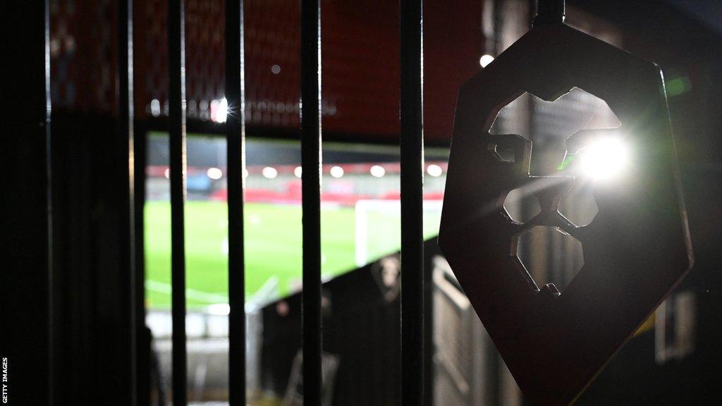 Salford's Peninsula Stadium, as seen through a gate