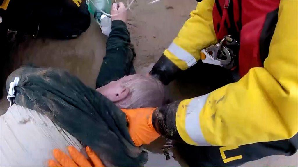 Mike Hall lying unconscious on the beach with RLNI team surrounding him