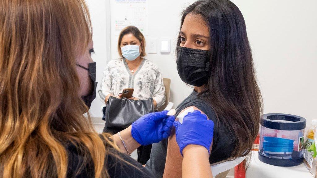 A 16-year old receives a dose of the Pfizer vaccine