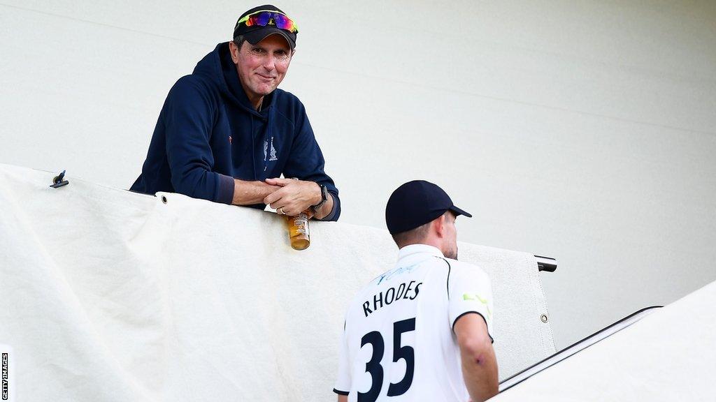 Warwickshire first-team coach Mark Robinson smiles at Will Rhodes coming up the stairs after winning a game in the County Championship