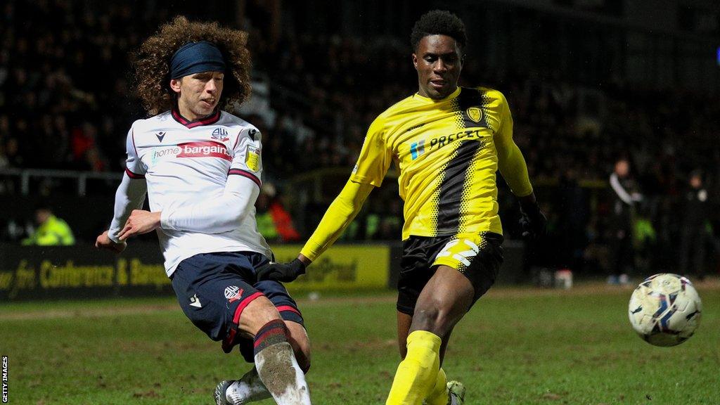 Williams Kokolo challenges for the ball with a Bolton player during a game in 2021