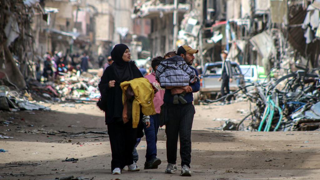 Palestinians look at destroyed buildings following the withdrawal of Israeli troops in Khan Younis, southern Gaza, on 10 April 2024