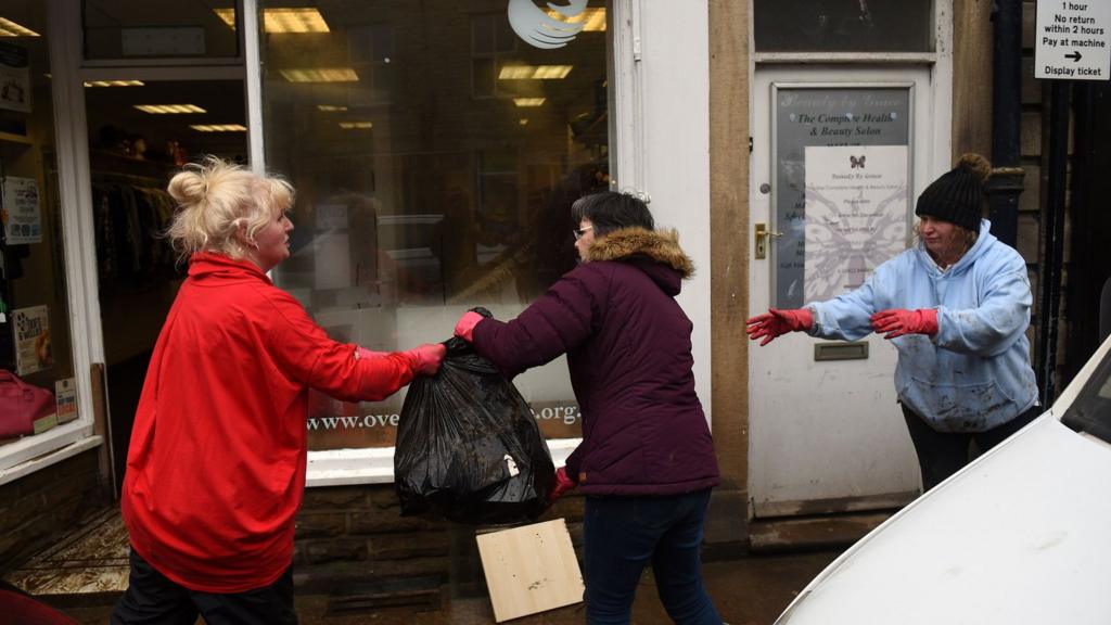 People help during the clean-up efforts at a business in Hebden Bridge after the flooding brought by Storm Ciara.