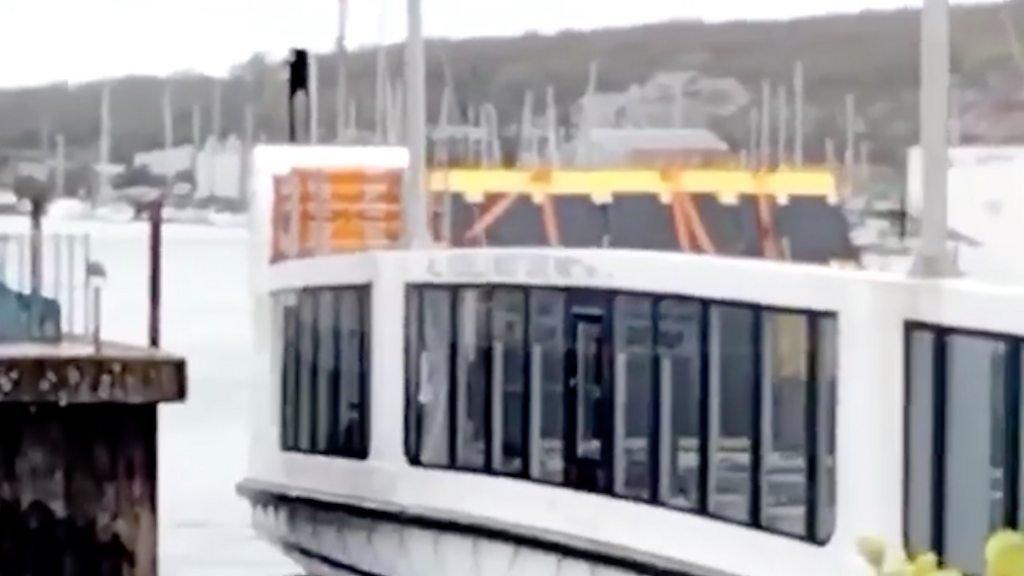 Cowes Floating Bridge with damaged windows next to sea wall.