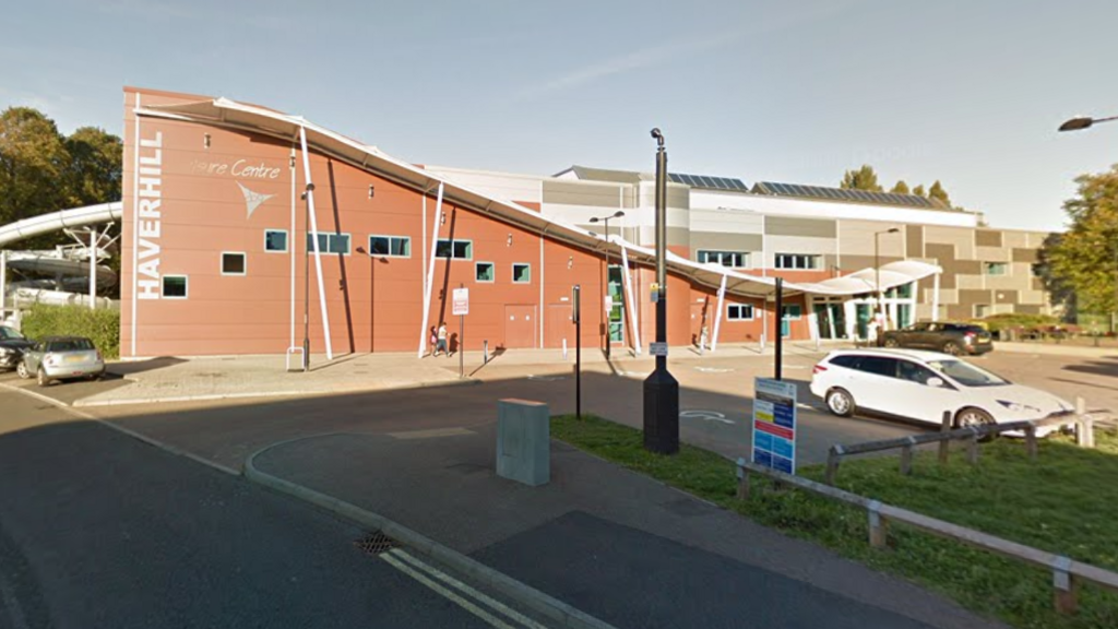 A Google Streetview image showing the outside Haverhill Leisure Centre, which is a brick built building with a wavy roof.