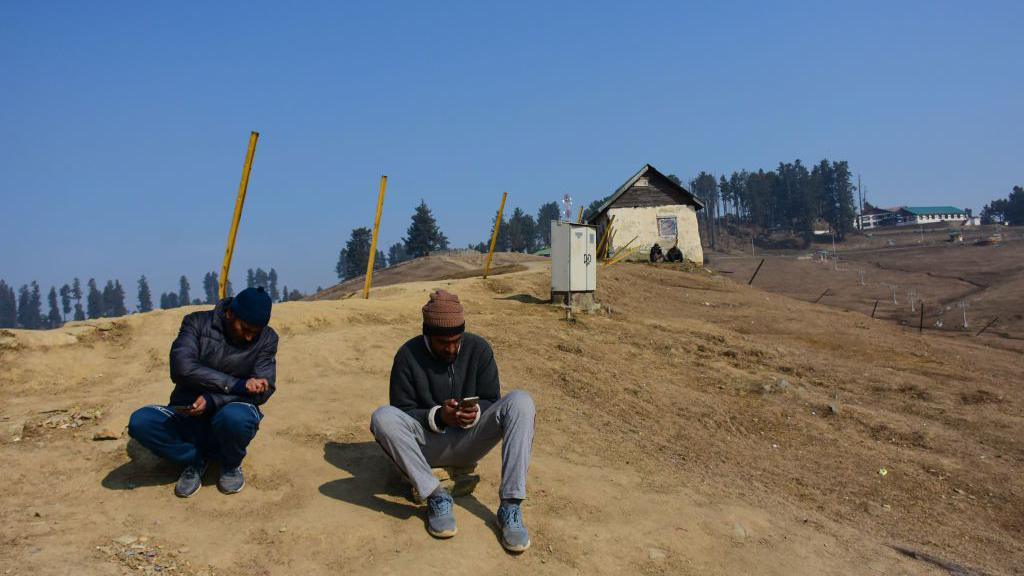 People are resting in the dry meadows, which are usually covered in a thick blanket of snow during winters, at Gulmarg, a ski destination in the Baramulla district of Indian-administered Kashmir, on January 23, 2024