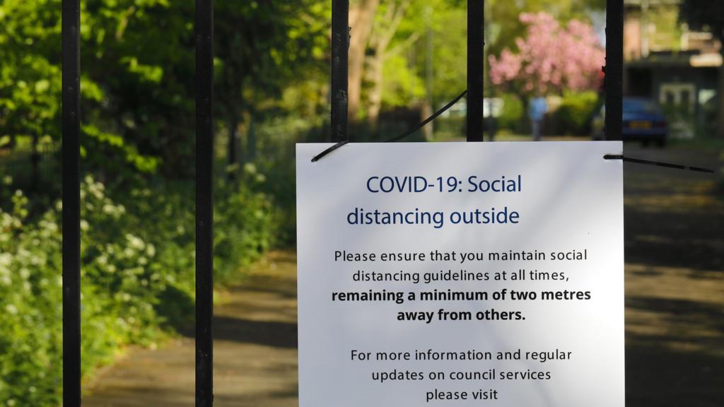 social distancing sign on park gates