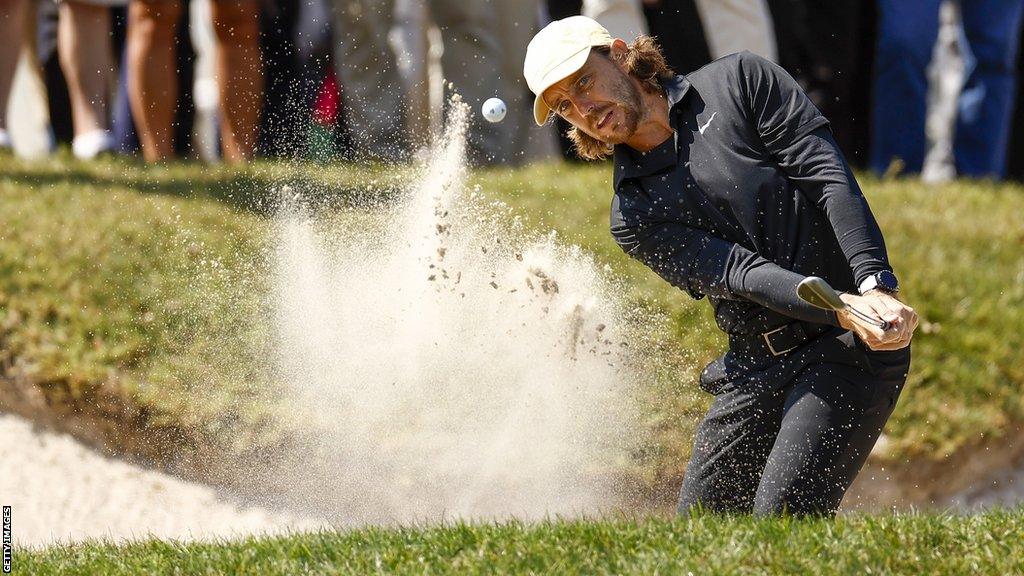 Tommy Fleetwood hits a shot from a bunker