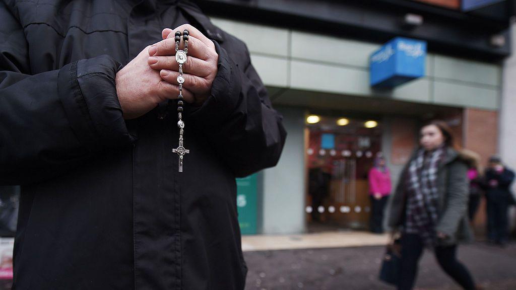 Man holding rosary beads outside abortion clinic 