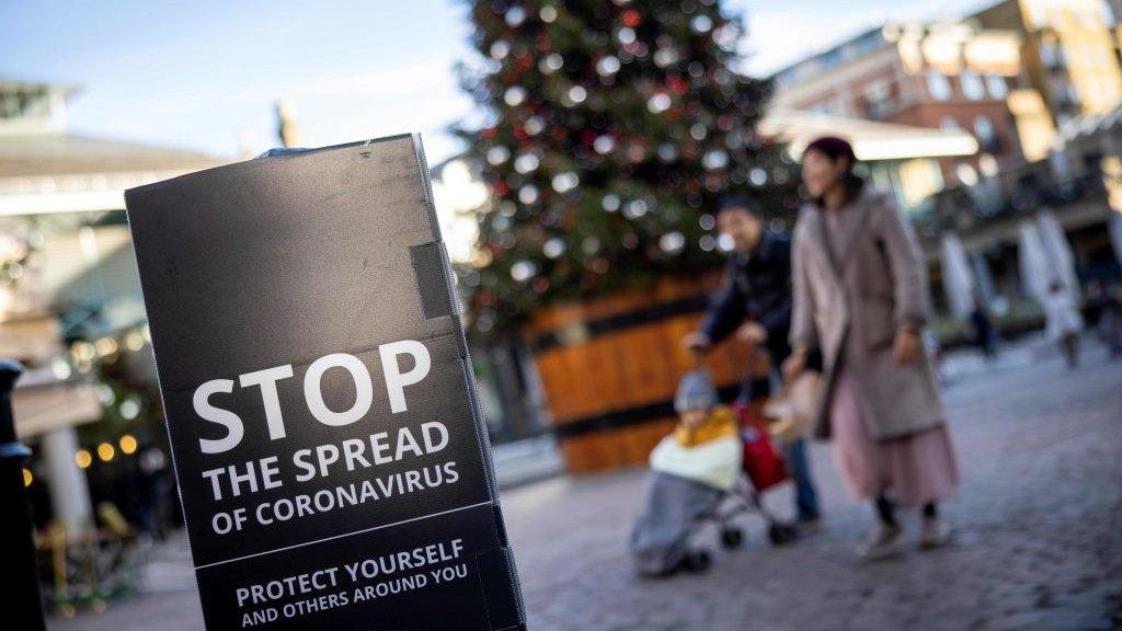 Coronavirus-sign-with-a-family-and-Christmas-tree-in-the-background.