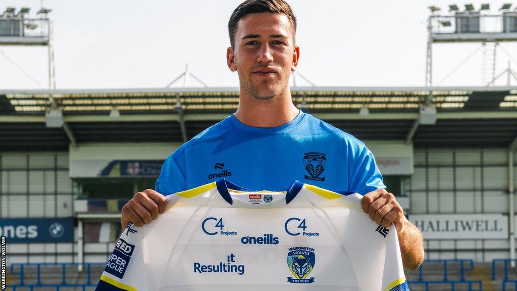 Wes Bruins holds a Warrington shirt for his signing photo