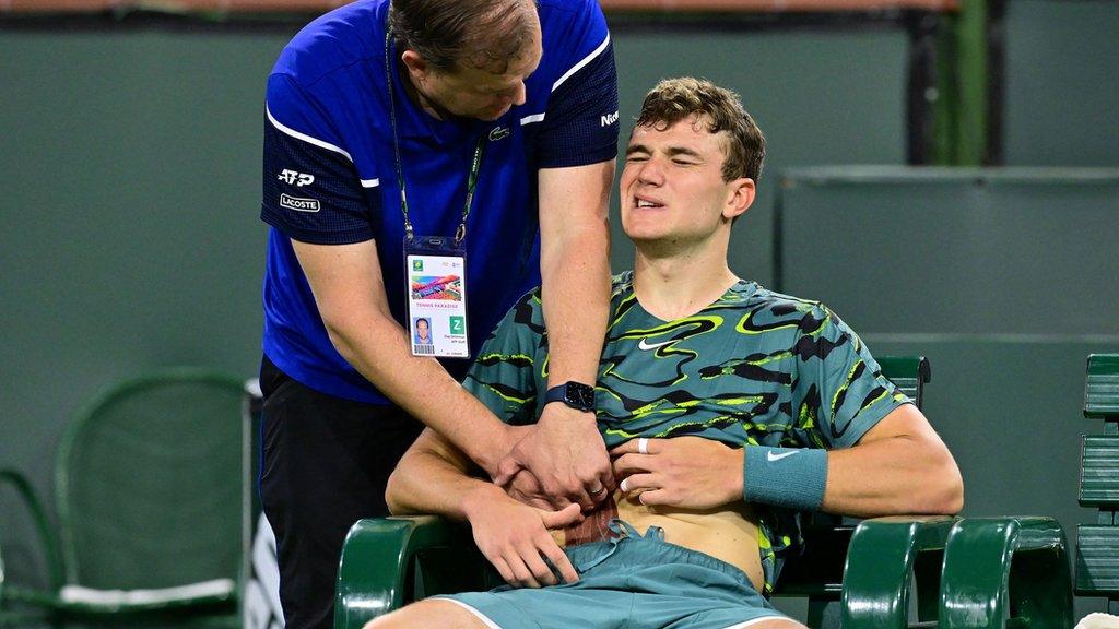 Jack Draper grimacing as he receives some treatment from the physio