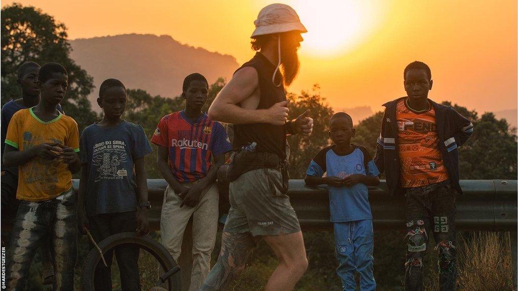 Russ Cook running along a road while being watched by locals