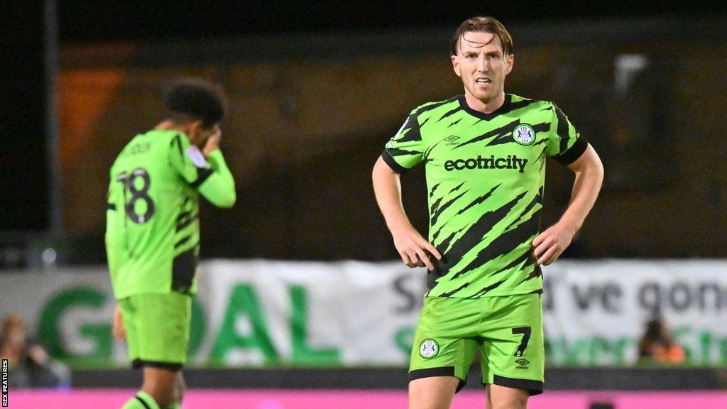 Forest Green's Kyle McAllister stands with his hands on his hips (right) while a team-mate covers his face with his hand behind