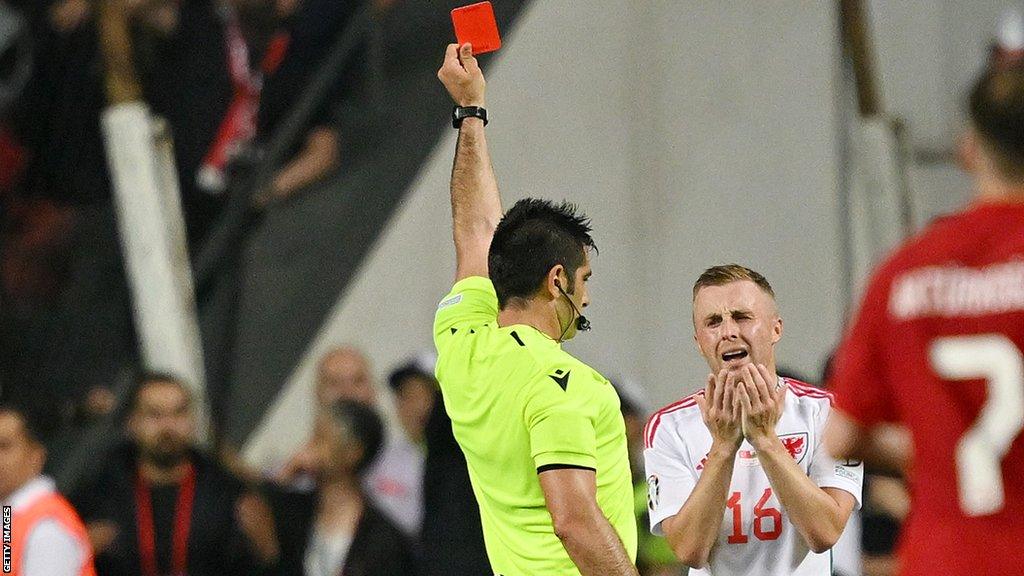 Referee Fabio Maresca shows a red card to Joe Morrell of Wales