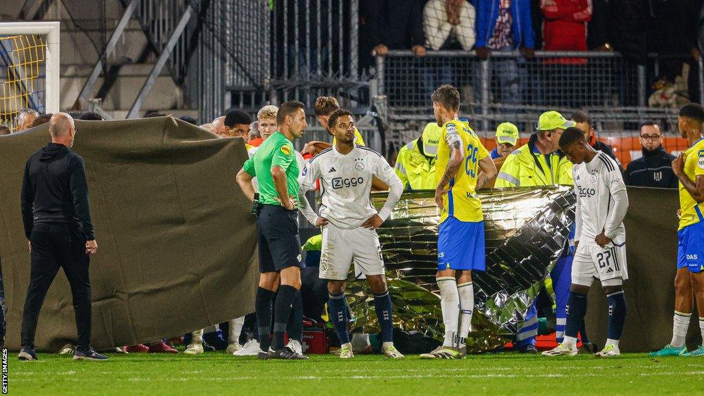 Players stand around Etienne Vaessen after head injury