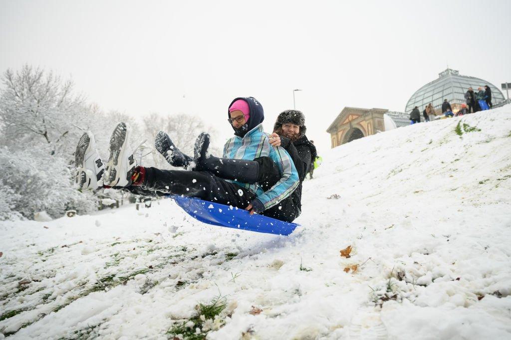 Two friends take to the air after hitting a ramp while sledging in Alexandra Park, London