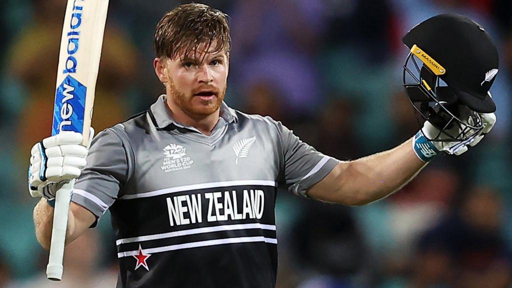 New Zealand batter Glenn Phillips raises his bat and helmet after hitting a century