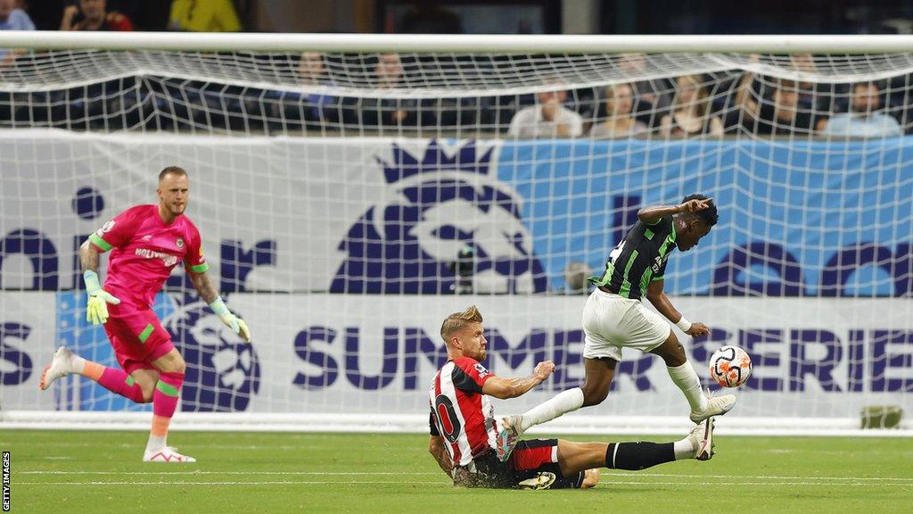 Brighton winger Simon Adingra beats the slide of Brentford defender Kristoffer Ajer to curl past Bees keeper Mark Flekken